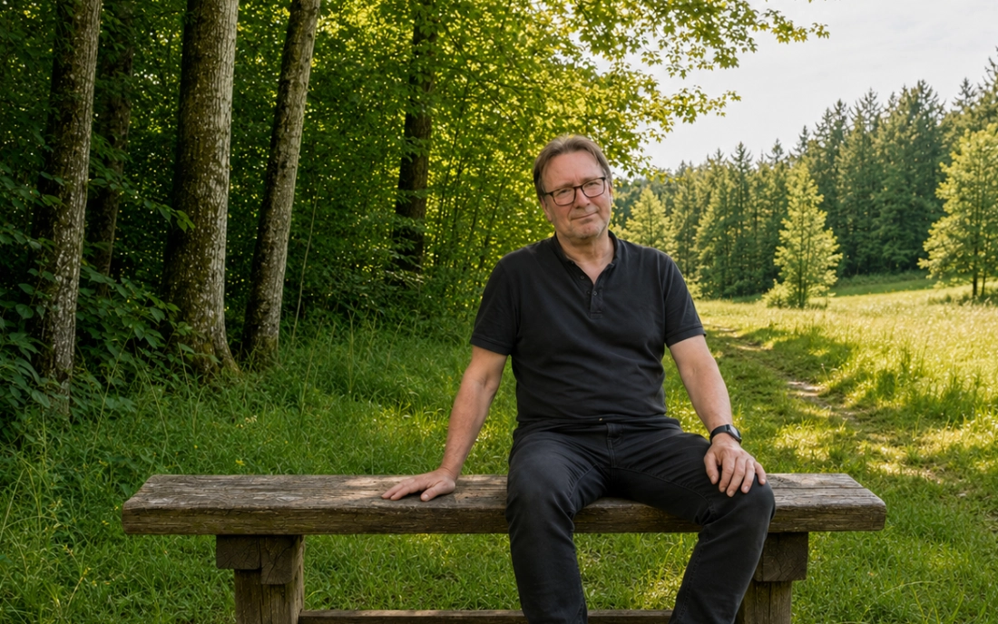 Hermann Schmidt sitzt im Naturraum auf einer Bank.